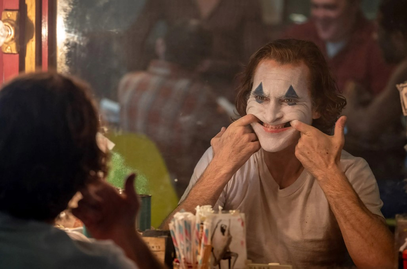 ▼《小丑》新剧照中,我们可以看见男主角瓦昆费尼克斯用食指强迫自己